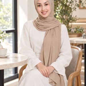 Woman seated in a bright café wearing a soft beige shawl